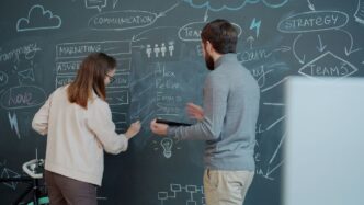 Two people collaborating on a chalkboard with diagrams.