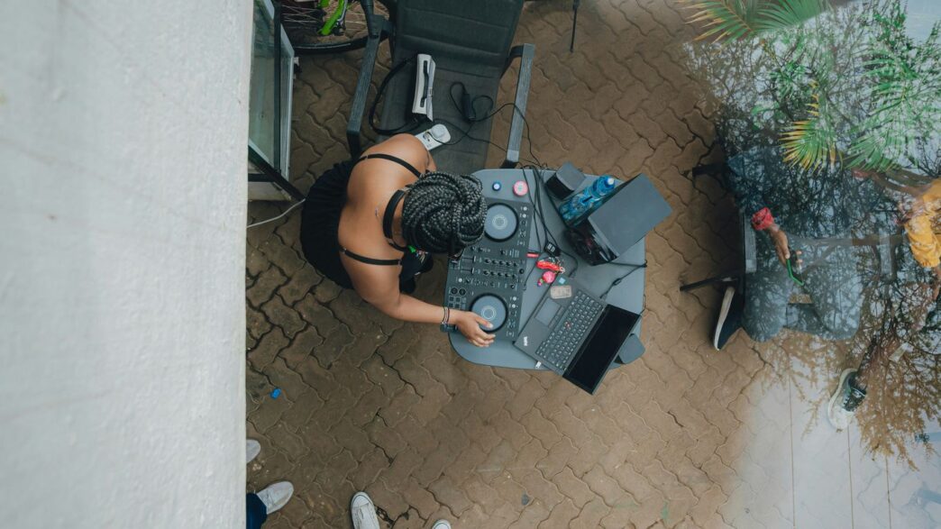 Dj playing music outdoors with a laptop and equipment.