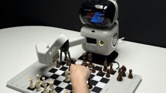 Robot arm playing chess with a human hand