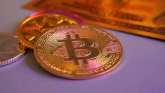 Golden bitcoin coin with other coins and card.