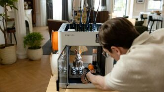 Man operating a 3D printer with a rabbit model.