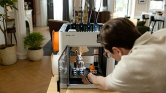 Man operating a 3D printer with a rabbit model.