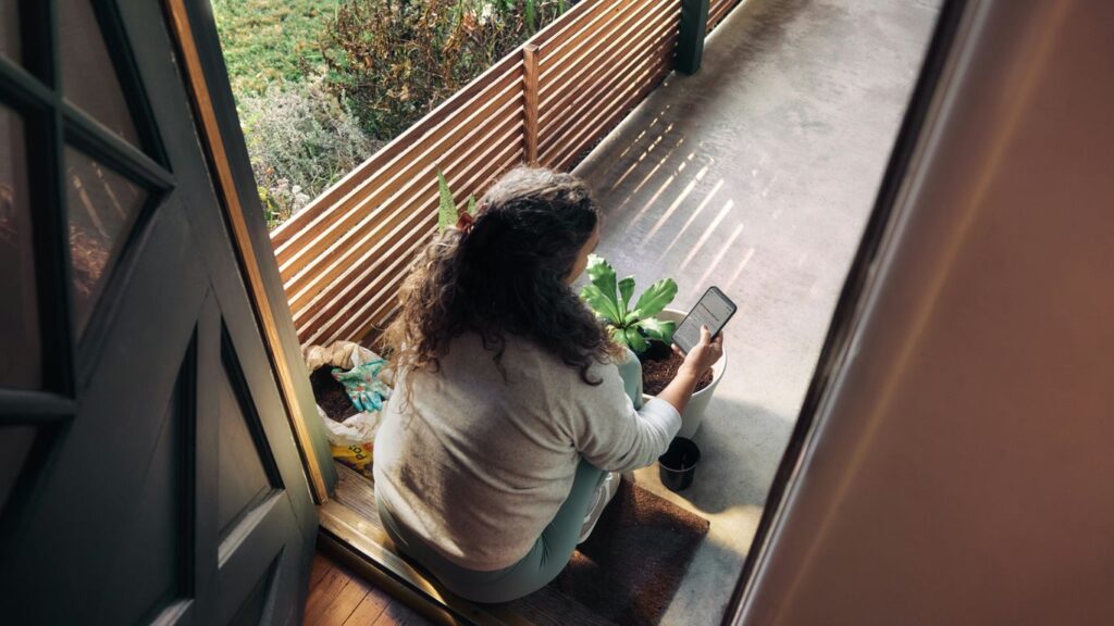 Woman sitting on balcony with smartphone