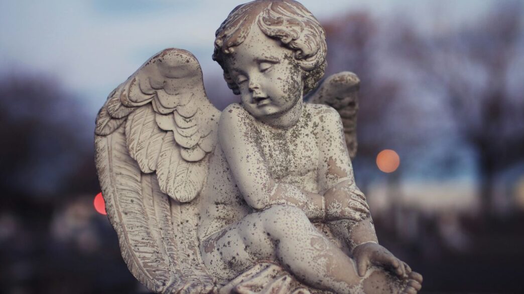 Stone angel statue in a cemetery at dusk