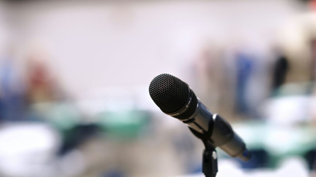 A microphone stands on a stand in an empty room.