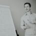 Man standing next to a whiteboard with notes.