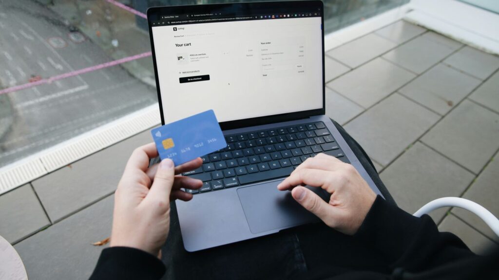 A person sitting in a chair with a laptop and a credit card