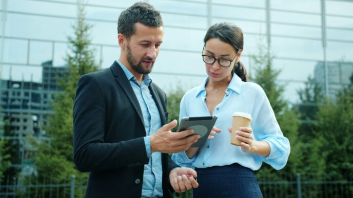 Man and woman looking at tablet outside building