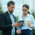 Man and woman looking at tablet outside building