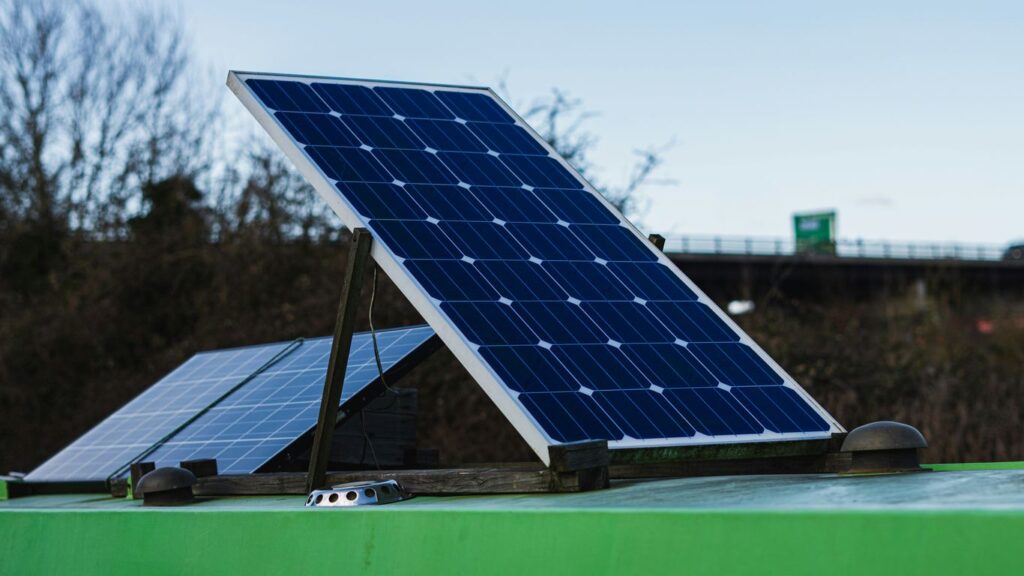 blue and white solar panel on green metal bar during daytime