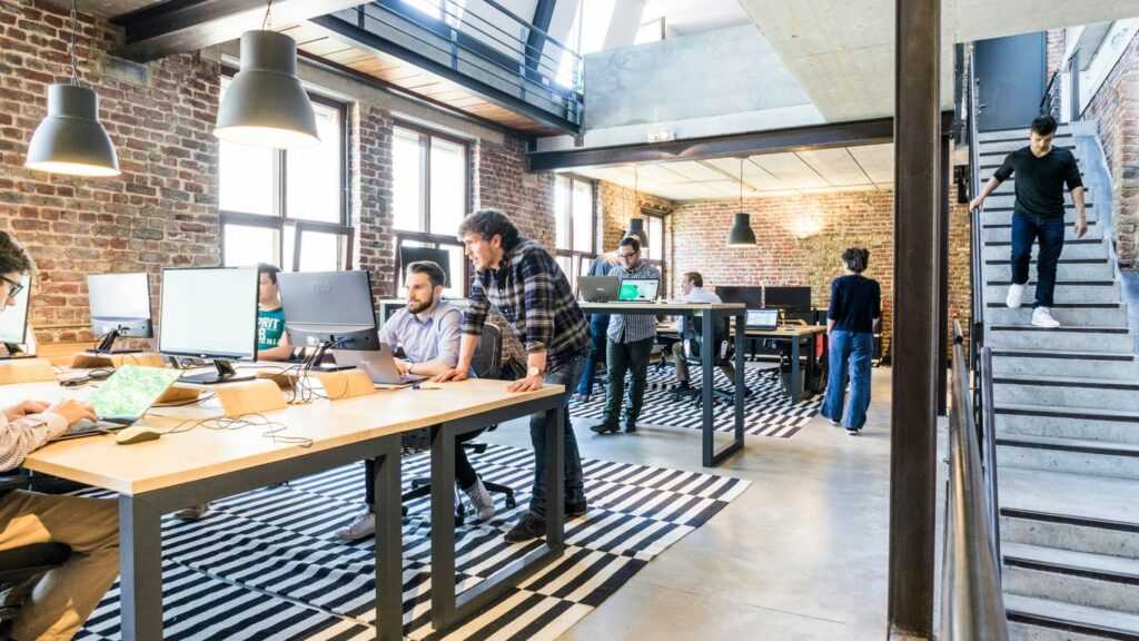 man standing beside another sitting man using computer