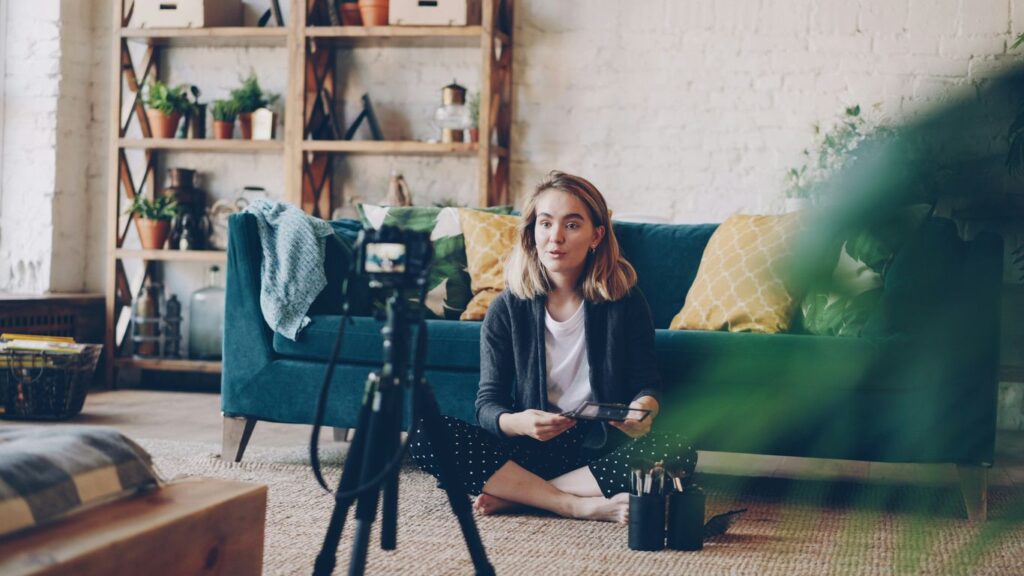 Woman filming herself with a camera in a living room.