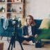 Woman filming herself with a camera in a living room.