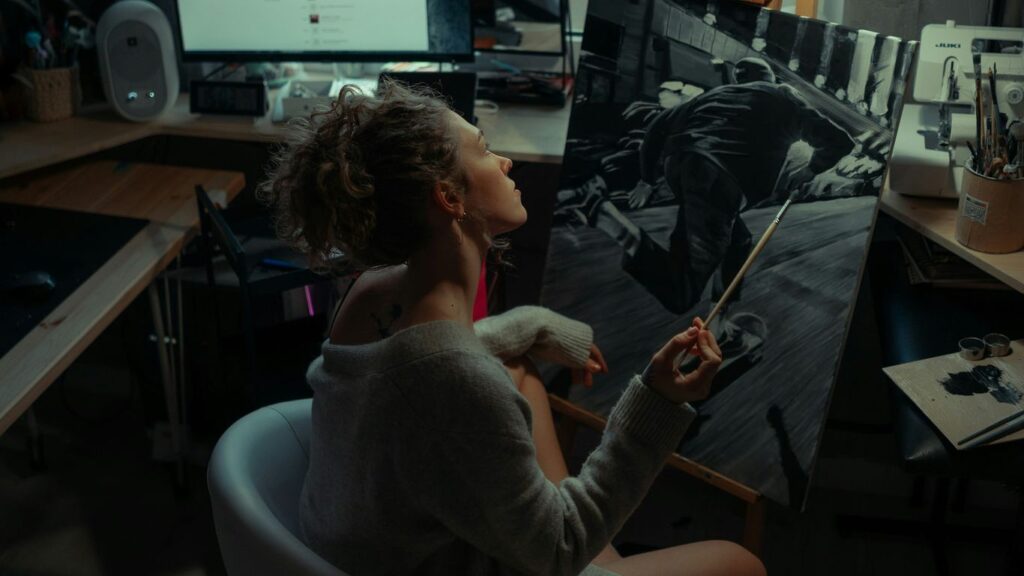 a woman sitting in a chair in front of a painting
