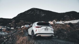 White suv parked on a gravel road near mountains.