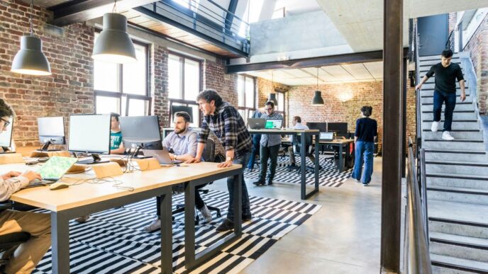 man standing beside another sitting man using computer