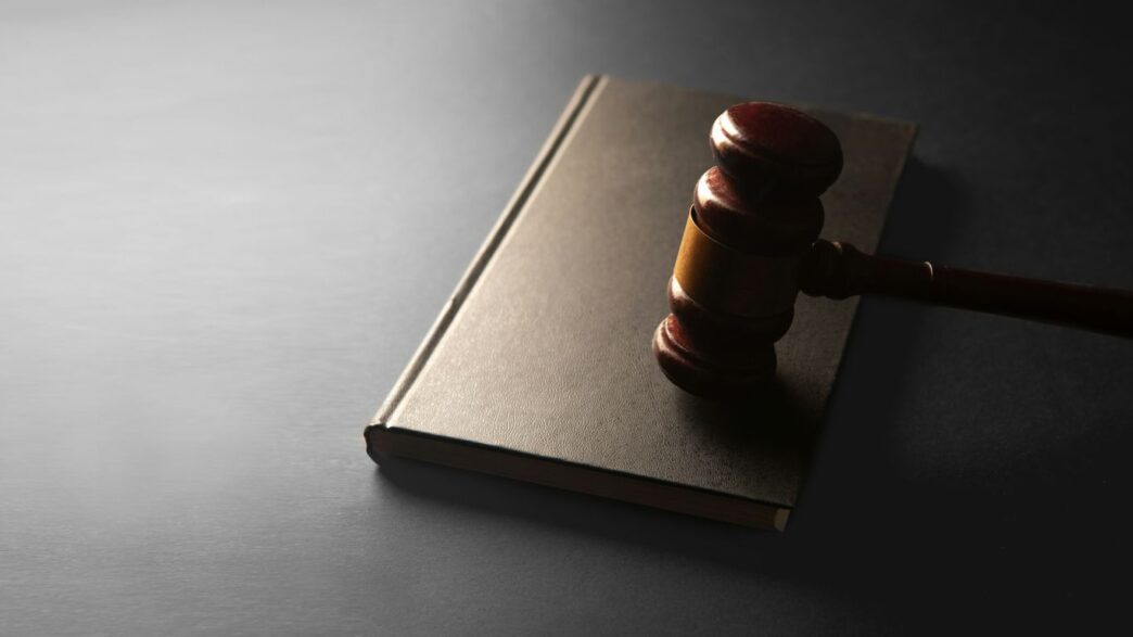 A wooden gavel rests on a closed book.