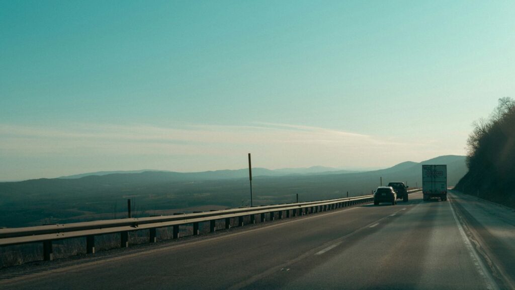 Trucks driving on a highway with distant hills.