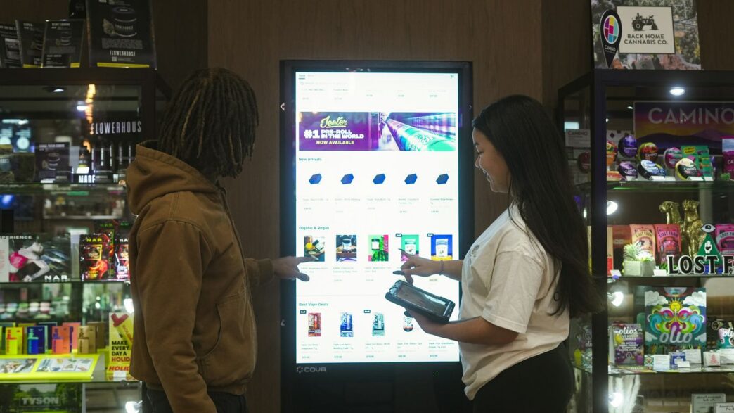 Two people interact with a digital display screen.