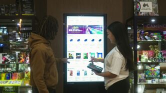 Two people interact with a digital display screen.