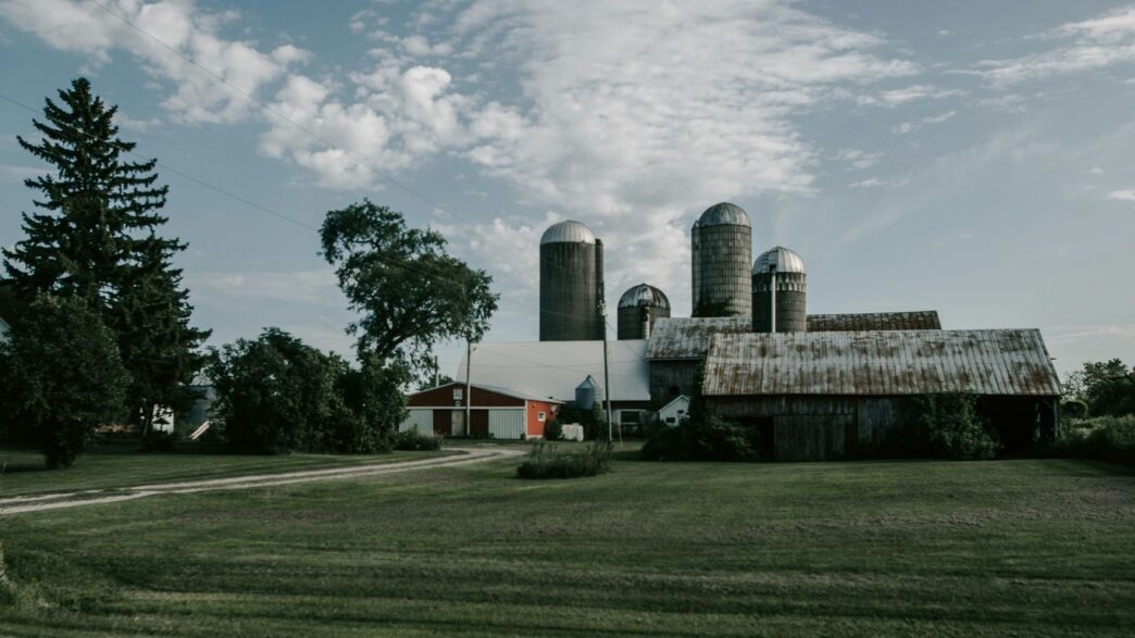 a farm with a barn and silos in the background