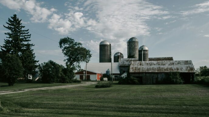 a farm with a barn and silos in the background