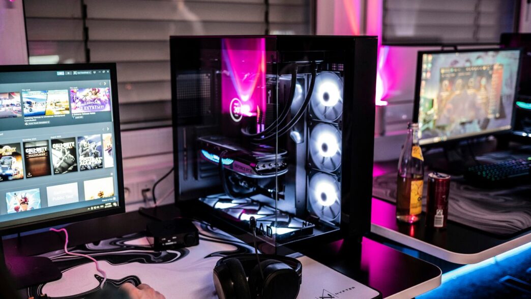 A man sitting at a desk with three computer monitors