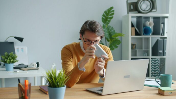 Man in yellow sweater drinking from mug at desk