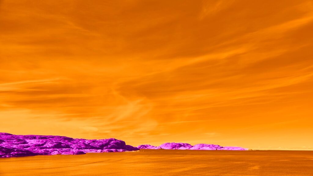 Vibrant orange sky over purple rocky coastline