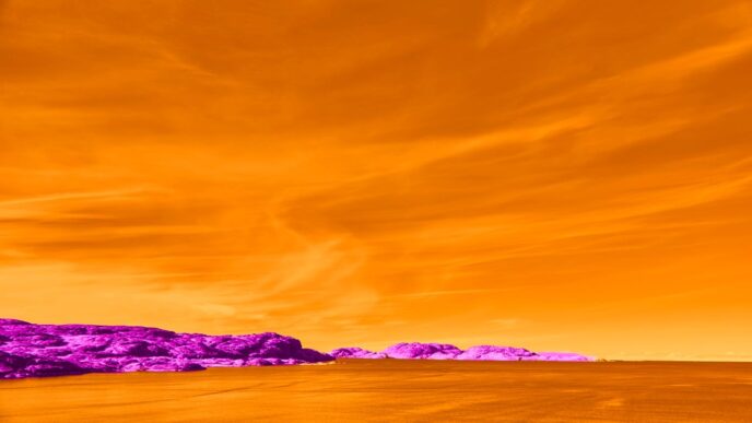 Vibrant orange sky over purple rocky coastline