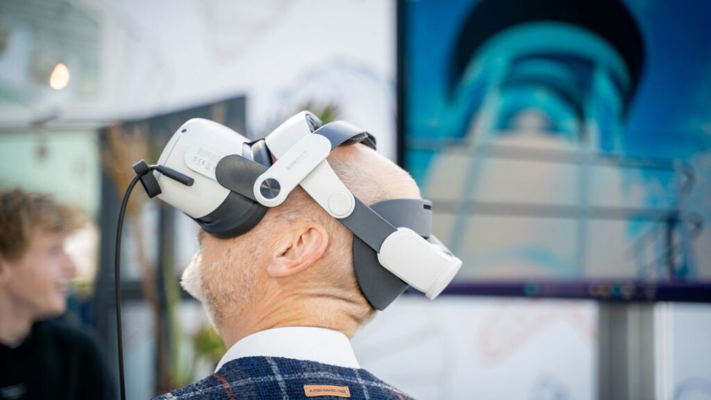 A man wearing a robot headpiece in front of a TV
