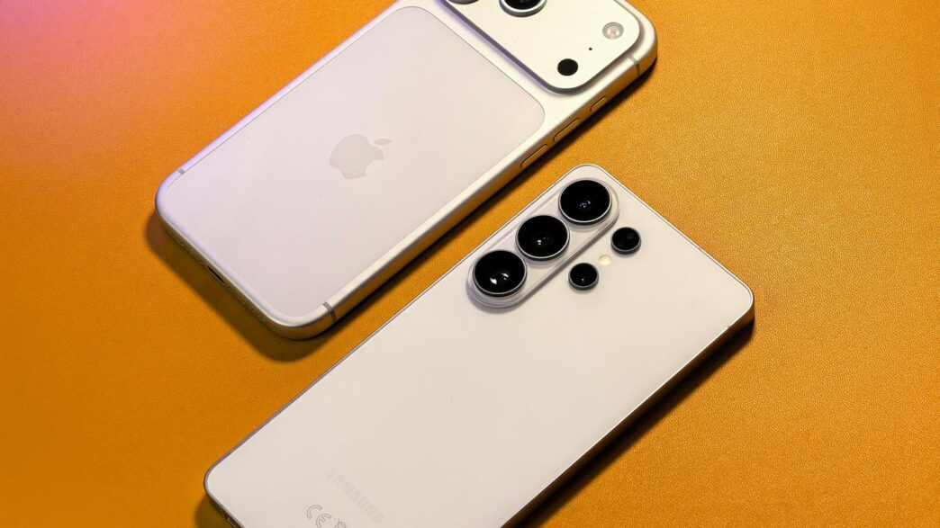 Two smartphones with multiple cameras arranged on orange surface