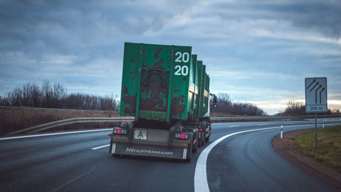 green freight truck passing by a winding road