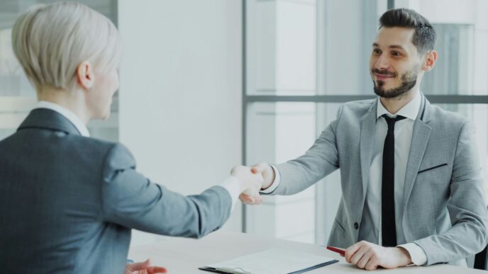 Two professionals shaking hands across a table.