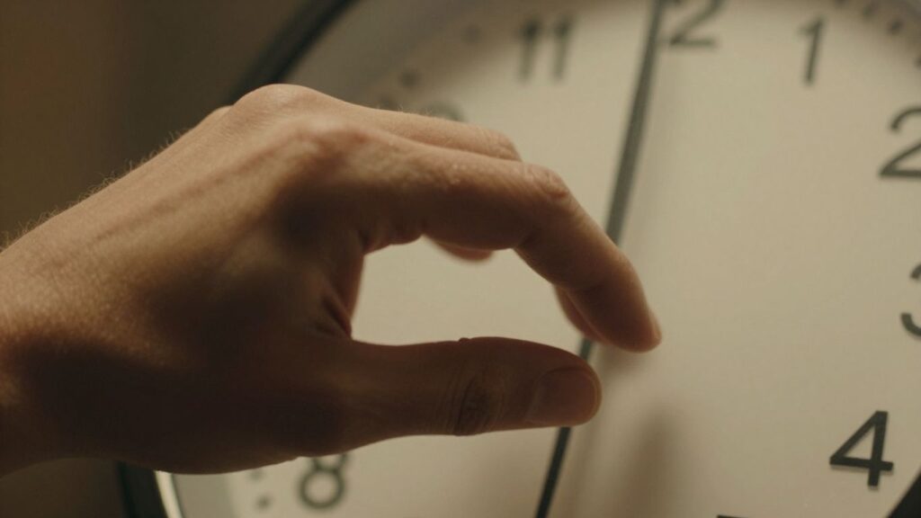 Hand reaching for a ticking clock, conveying urgency.