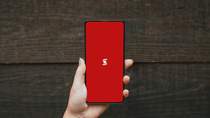 a person holding a red cell phone in their hand