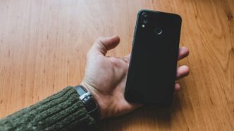 a person holding a cell phone on a wooden table