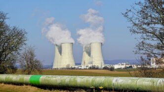 Cooling towers emitting steam against a clear sky.