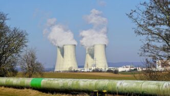 Cooling towers emitting steam against a clear sky.