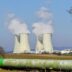 Cooling towers emitting steam against a clear sky.