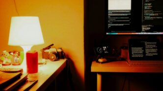 Desk with computer, lamp, and vintage camera.