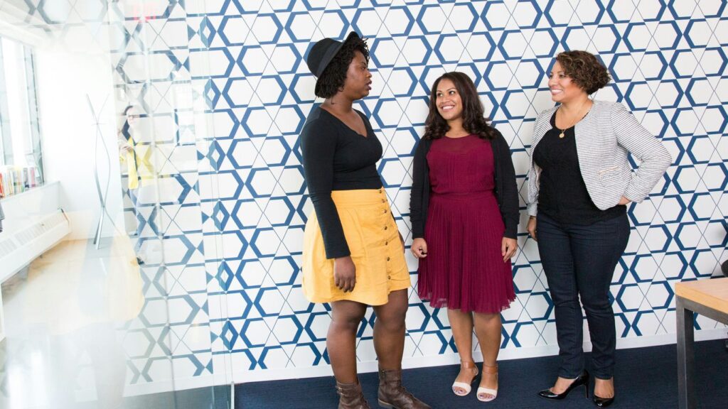 three standing women talking to each other