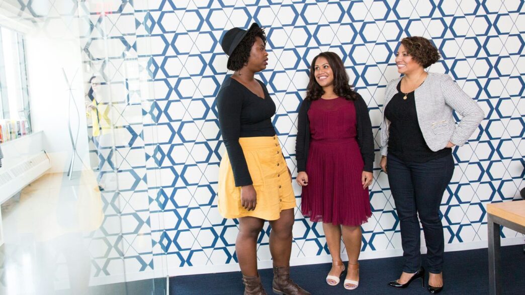 three standing women talking to each other