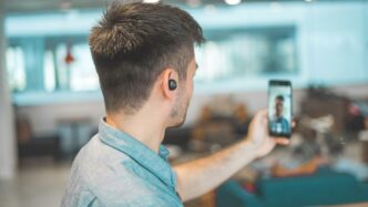shallow focus photo of man in gray collared top taking selfie