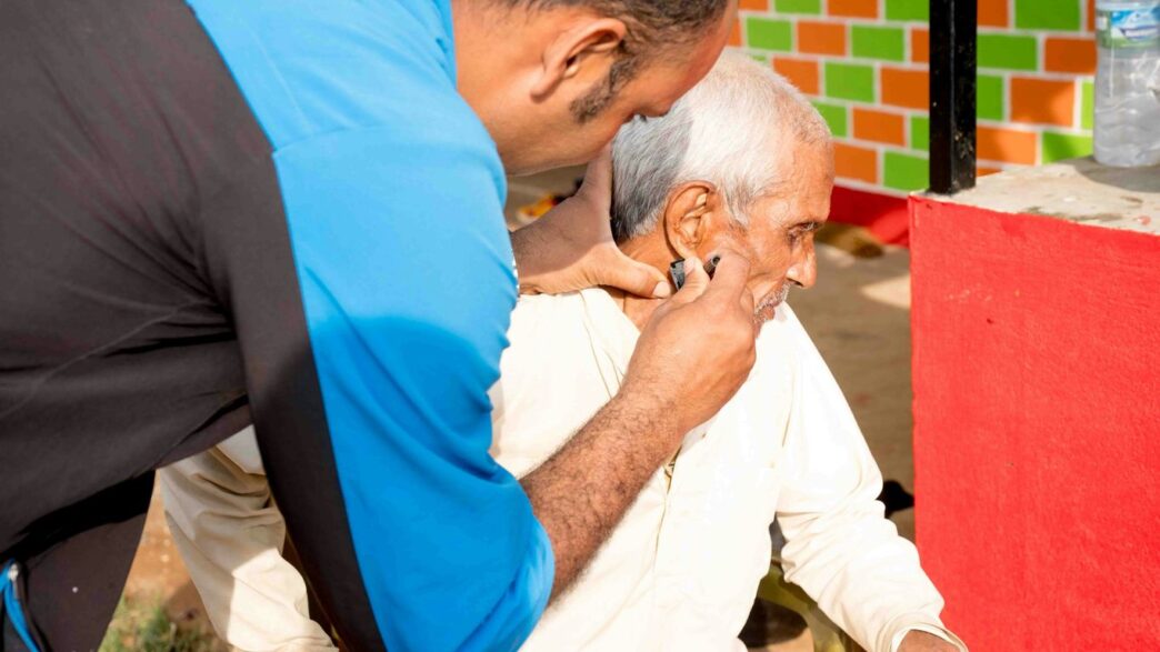 a man getting his hair cut by a man in a blue shirt