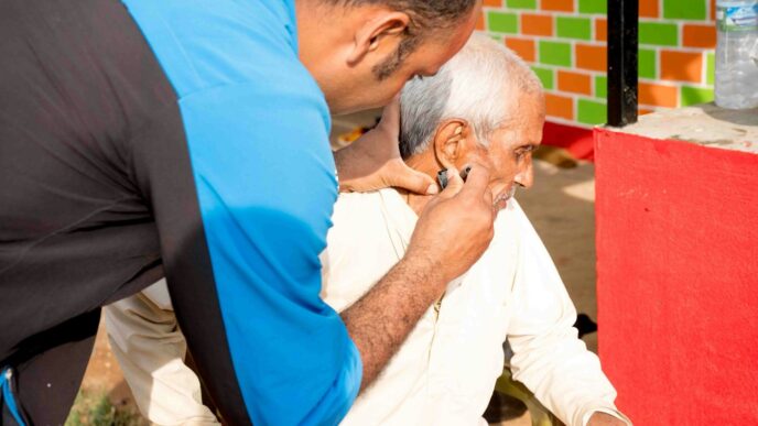 a man getting his hair cut by a man in a blue shirt