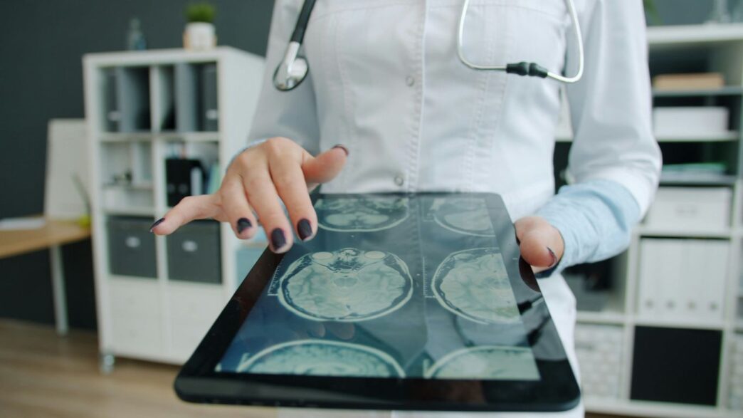 Doctor shows brain scan on tablet in office