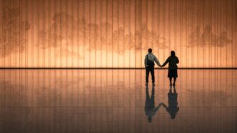 Couple holding hands in front of illuminated wall