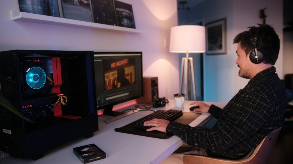 a man wearing headphones and sitting at a desk with a computer