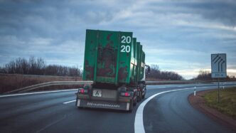 green freight truck passing by a winding road